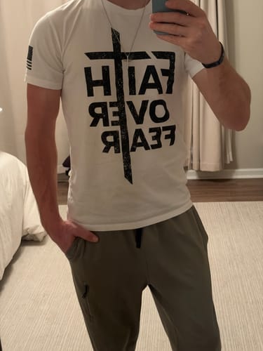 Reviewer showing the fit of their white graphic FEARLESS TEE in a mirror selfie.
