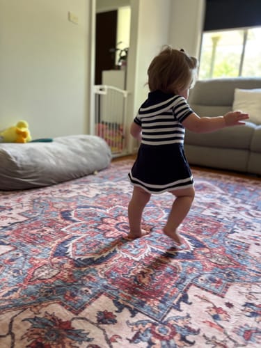 A customer's toddler walking on the colorful Mellow Mat Designer Print rug in a living room.