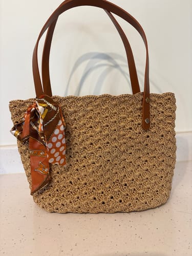 Customer's finished Aveline crochet Shoulder Bag in light brown, shown with leather handles and a patterned scarf tied to the side.