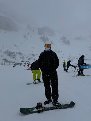 Reviewer on a snowboard wearing the baggy snow pants in black on a snowy slope.