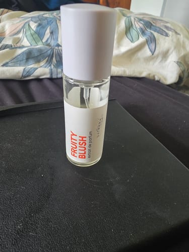 Customer's bottle of 'Fruity Blush' perfume received as the Mystery Gift, standing on a dark surface.