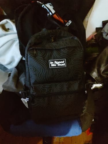 Customer's black 'Pathway' backpack with a topographic pattern, showing the front pocket and 'In Speed We Trust' logo.
