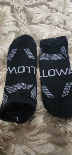 Reviewer's pair of black Men's Alpaca Socks from Willowace laid flat on a patterned surface.