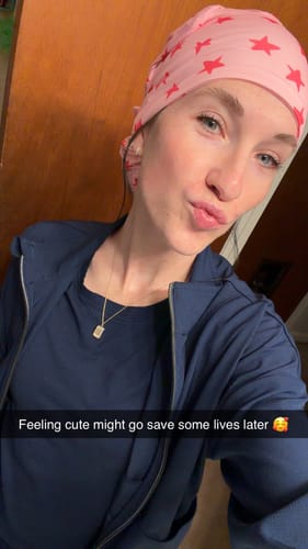 A reviewer selfie showing the pink DuoStyle Scrub Hat with a red star pattern worn with navy scrubs.