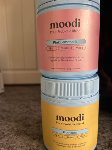 Customer's tub of moodi Pink Lemonade supplement stacked on top of another tub of the Tropicana flavor.