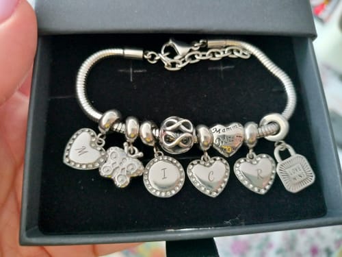 A customer's silver Embellap bracelet with multiple custom charms, including initials and hearts, presented in a gift box.