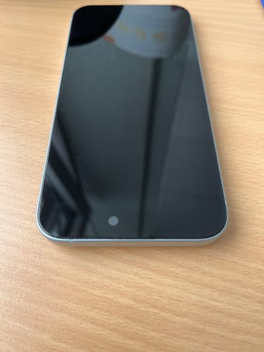 Rezensent zeigt die 3-in-1-Schutzfolie, die auf einem iPhone auf einem Holztisch angebracht ist.