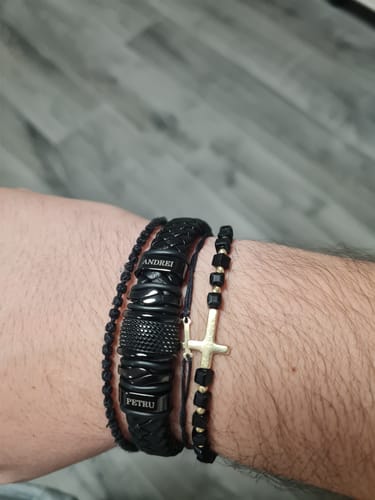 Customer wearing the personalized black bracelet with the names 'Andrei' and 'Petru' on their wrist, stacked with other bracelets.