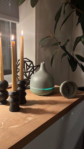 Recensent toont de ingeschakelde Close 2 Nature 3.0 diffuser op een dressoir bij sfeervol kaarslicht.
