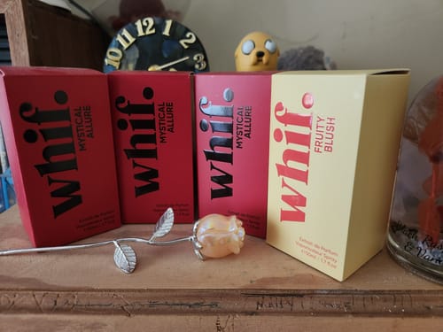 Reviewer's collection of Whif perfumes, with three red Mystical Allure boxes and one yellow Fruity Blush box on a shelf.