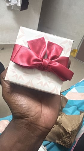 Customer holding the patterned white gift box for the Silver Glittering Ring, tied with a red bow.