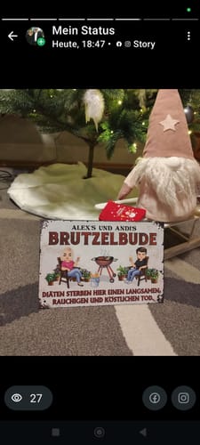 Kunde zeigt das personalisierte Gartenschild 'Brutzelbude' als Weihnachtsgeschenk unter einem Baum.