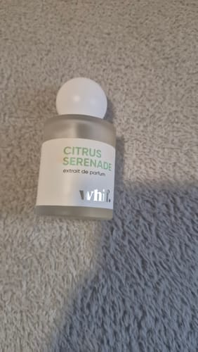 A customer's bottle of Citrus Serenade perfume with a white cap, shown on a soft, grey surface.