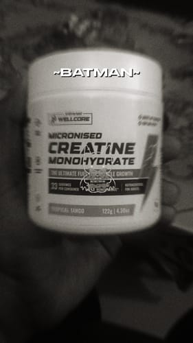 Close-up of a customer holding a white tub of Wellcore Micronised Creatine Monohydrate in a black and white image.