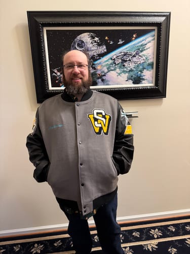 Reviewer showing the front of the grey and black Star Wars "A Long Time Ago...." Varsity Jacket.