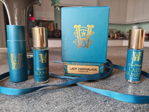 Customer's teal Lady Marmalade perfume box with two travel-size fragrances arranged on a countertop.