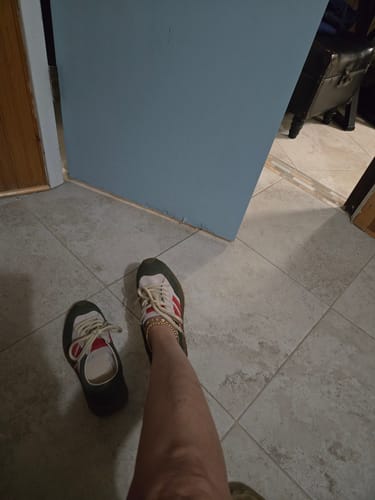 Customer wearing one vintage colorblock sport shoe with its match on the floor beside them.