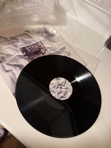 Customer's custom vinyl record displayed with its personalized sleeve featuring a crumpled paper design.