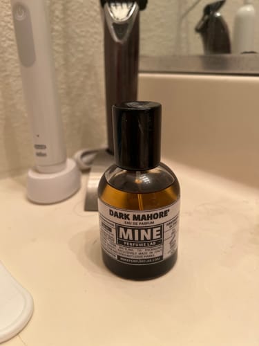 Recensore mostra la sua boccetta di profumo DARK MAHORE sul mobile del bagno.