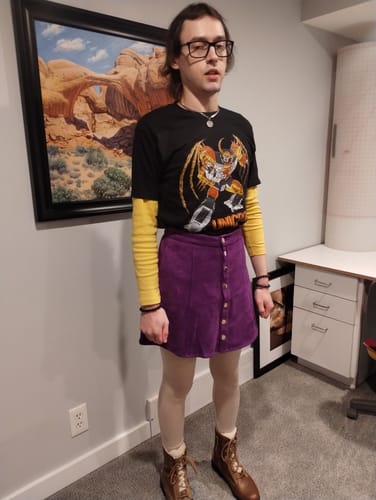 Reviewer wearing the black Transformers Unicron Shirt layered over a yellow shirt with a purple skirt and boots.