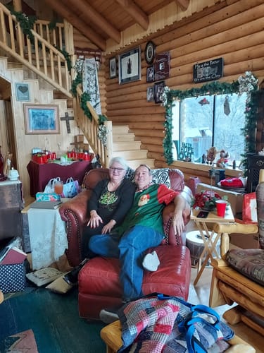 A person wearing the festive Sweet Papa Christmas Button Up shirt while relaxing with another person on a chair.