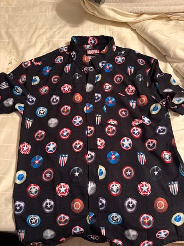 Customer's black 'Wield the Shield' shirt laid flat, showing the detailed all-over pattern of various Captain America shields.