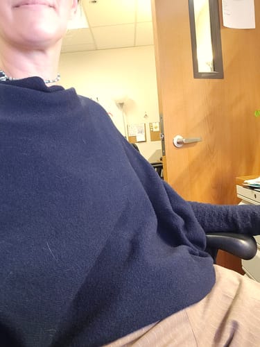 Reviewer sitting in an office wearing the navy Asymmetric Draped Seamless Knit top.