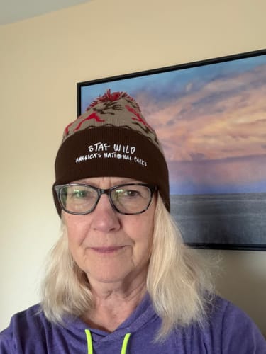 Customer wearing the Stay Wild Beanie, showing its brown cuff with embroidered text and patterned top with a pom-pom.