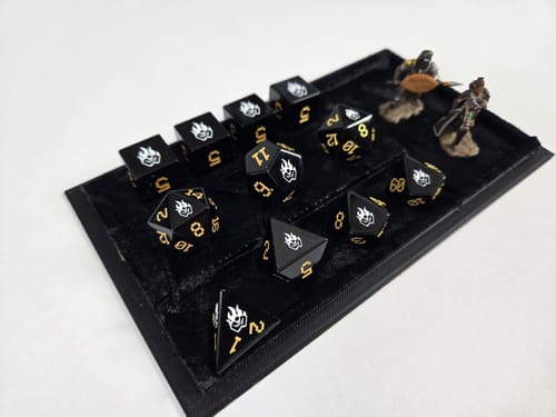 Customer's custom order dice set arranged in a black tray. The black dice feature gold numbers and a white logo.