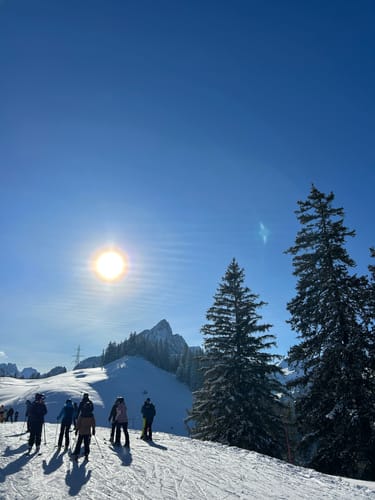 Reviewers wearing snow jackets on a sunny day on a snow-covered mountain.