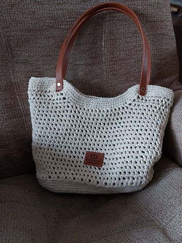 Customer's completed off-white Sunny Beach Tote with brown straps, shown resting on a textured brown sofa.