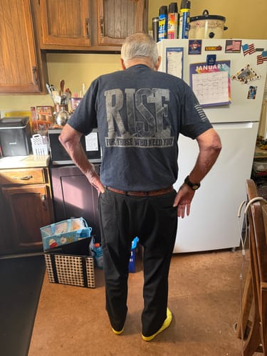 Customer from behind wearing a dark T.V.P. Elite Membership t-shirt with a large 'RISE' graphic on the back.