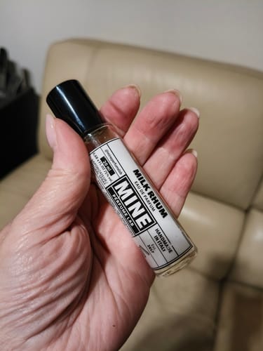 Recensore tiene in mano la boccetta di vetro del profumo MILK RHUM, mostrando l'etichetta.