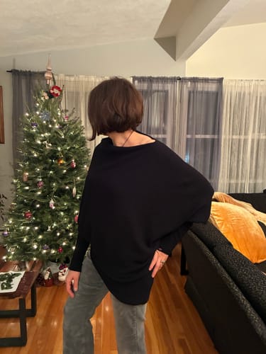 Customer wearing the black Asymmetric Draped sweater, showing the oversized fit from the side.
