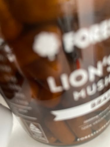 Customer's blurry, close-up photo of the Australian Grown Lions Mane Mushroom Capsules jar with capsules visible inside.