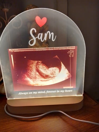 Recensent toont een verlichte Echo Fotolamp, gepersonaliseerd met een echofoto, de naam Sam en een tekst.