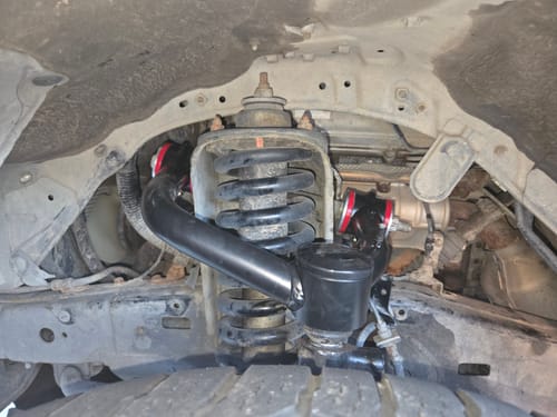Customer's view of the black Upper Control Arms with red bushings installed in their vehicle's suspension.