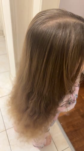 Cliente montrant les longs cheveux de sa fille après le brossage avec la brosse démêlante anti-casse.