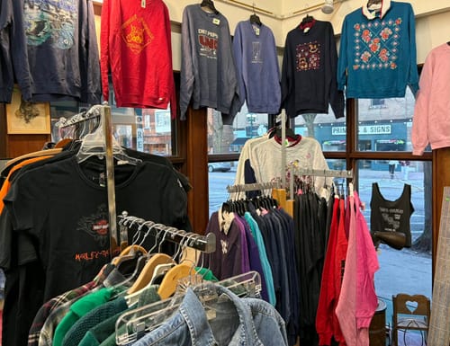 Reviewer's selection of assorted vintage graphic sweatshirts hanging on multiple racks in a shop.