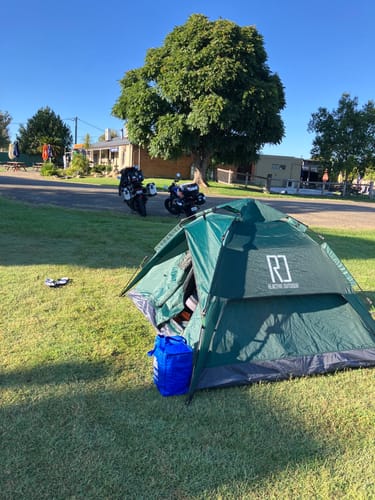 Customer's green Large-Sized 3 Secs Tent set up on a sunny day at a campsite with two motorcycles nearby.