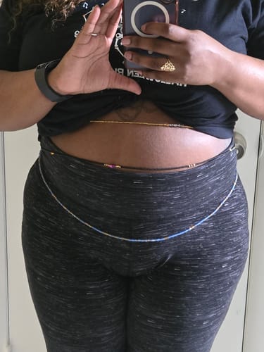 Reviewer wearing blue and gold Aquarius Tie On Waist Beads with a crop top and leggings.