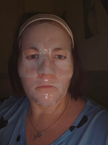 Eine Rezensentin trägt die durchscheinende Kollagen Boosting Maske im Gesicht.