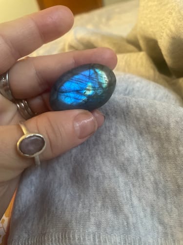 Reviewer holding a polished Labradorite Moonstone with blue iridescence.