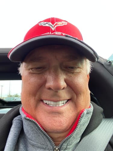 Reviewer smiling in a car, showing off a bright, white smile with their Spare Veneers.