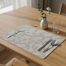 Anmelderens grå bordbrikke med løvmønster, dekket på et spisebord i tre.