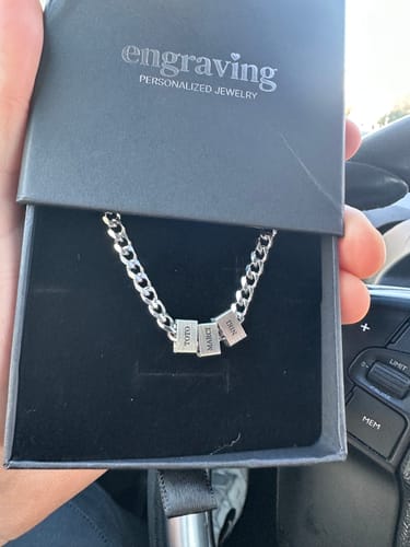 Customer shows their personalized Legacy necklace with three engraved name beads resting inside its black jewelry box.