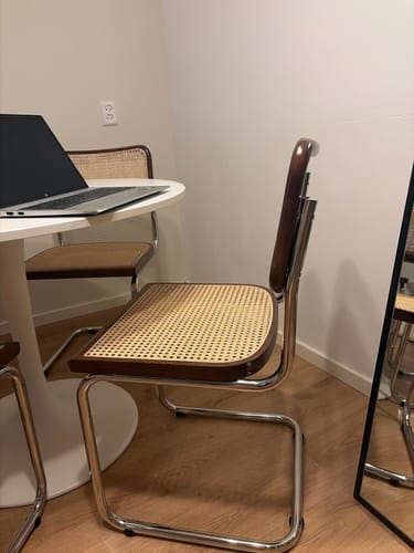 Recensentfoto van de Wave eetkamerstoel in walnoot en chroom, geplaatst in een eethoek bij een witte tafel.