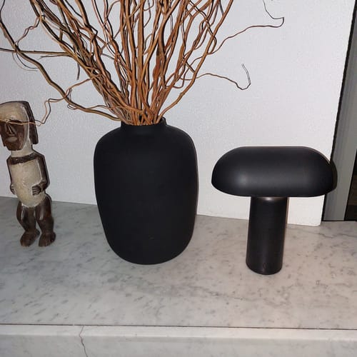 Recensent toont de zwarte, snoerloze Porta tafellamp op een marmeren blad.