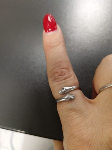 Customer wearing their Mystery Gift, a silver ring shaped like two hands hugging their thumb.