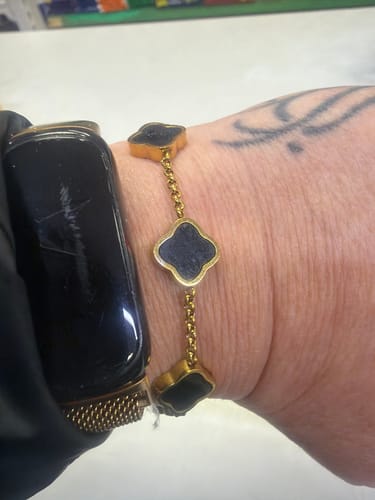 Reviewer wearing the Celine Clover Bracelet with black enamel clovers on their wrist.